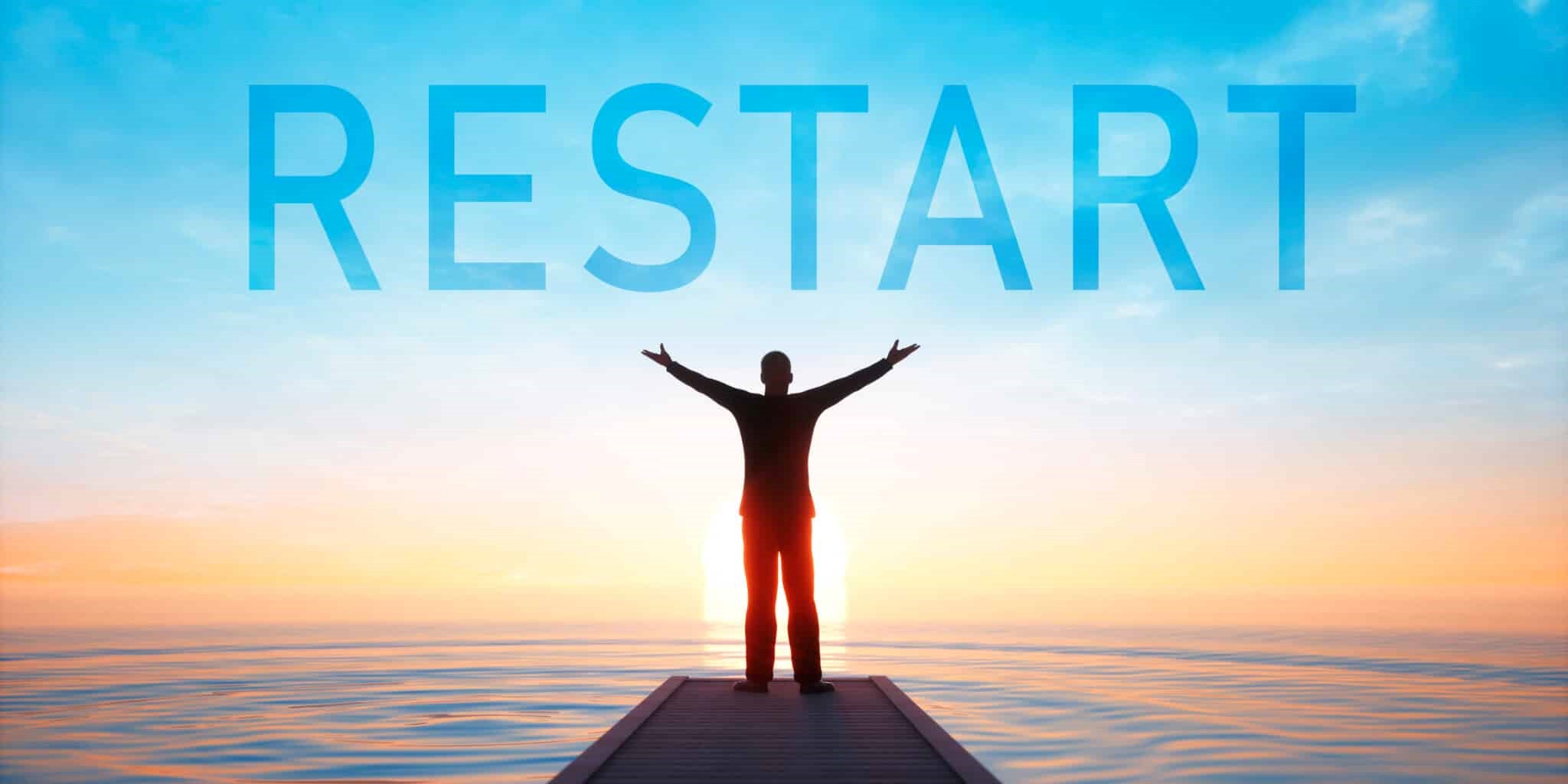A person standing in front of Restart text in the sky